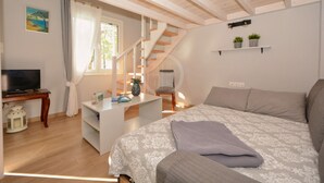 Ein Schlafzimmer mit Bett, Schreibtisch, Stuhl, Fernseher und einer Treppe.