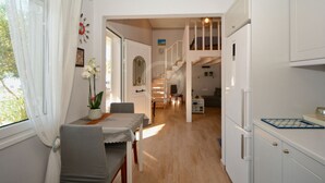 Eine geräumige Küche mit weißen Schränken, ein Essbereich mit Tisch und Stühlen sowie eine Treppe, die in einen oberen Bereich führt.