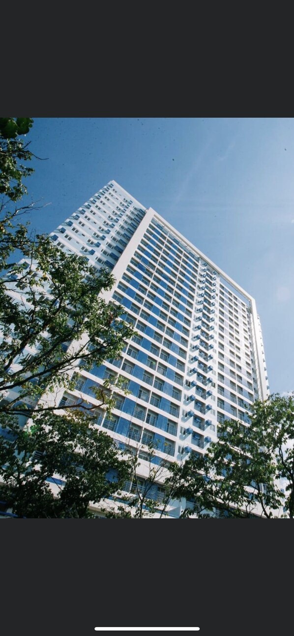 Located in an urban setting, this high-rise building features a grid-like facade with numerous windows and balconies.