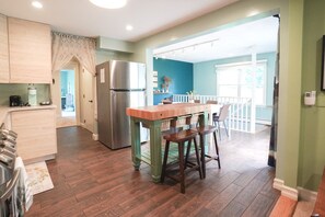 A kitchen with wooden cabinets, a stainless steel refrigerator, and a wooden island with stools.