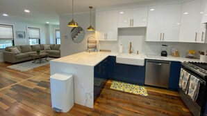 A modern kitchen with white cabinets, a marble island, and a built-in dishwasher.