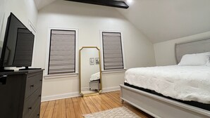 A bedroom with a bed, dresser, vanity, and a ceiling with exposed beams and recessed lighting.