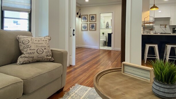 A living room with a beige sofa, a round wooden coffee table, and a potted plant.