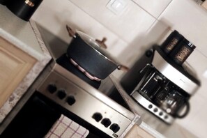 Een keuken met een fornuis, een koffiezetapparaat en een pan op het fornuis.