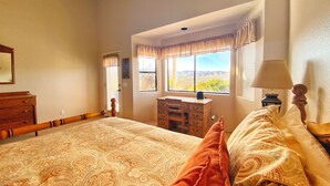 A bedroom with a large bed, a desk, and a window with a view of the landscape. - Views, views, views! Spacious home with Red Rock & Sunset Views. Near the river! (Clarkdale)