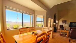 A dining area with a wooden table and chairs, a television, and a fireplace. - Views, views, views! Spacious home with Red Rock & Sunset Views. Near the river! (Clarkdale)