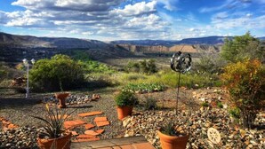 A garden with potted plants and a metal sculpture, set against a backdrop of a mountainous landscape under a partly cloudy sky. - Views, views, views! Spacious home with Red Rock & Sunset Views. Near the river! (Clarkdale)