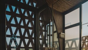 A room with a wooden bench, a towel rack, and a view through a lattice window. - Chozos Resort (Ugarteche)