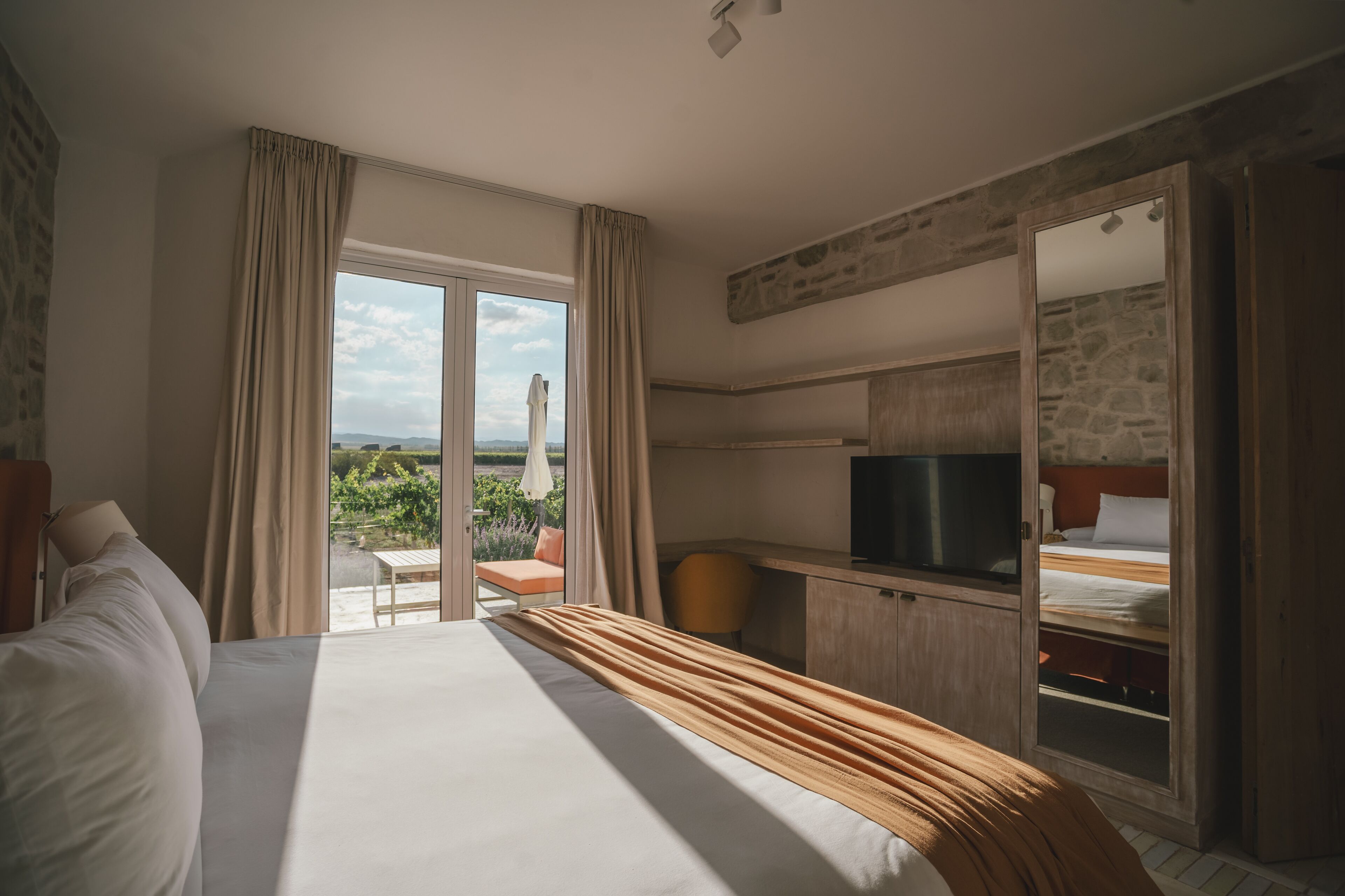 Habitación de hotel con cama, escritorio, televisión y vista al exterior.