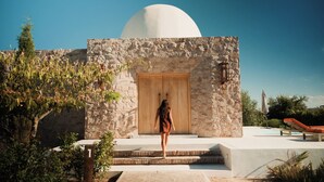 A woman approaching a stone building with a large dome. - Chozos Resort (Ugarteche)