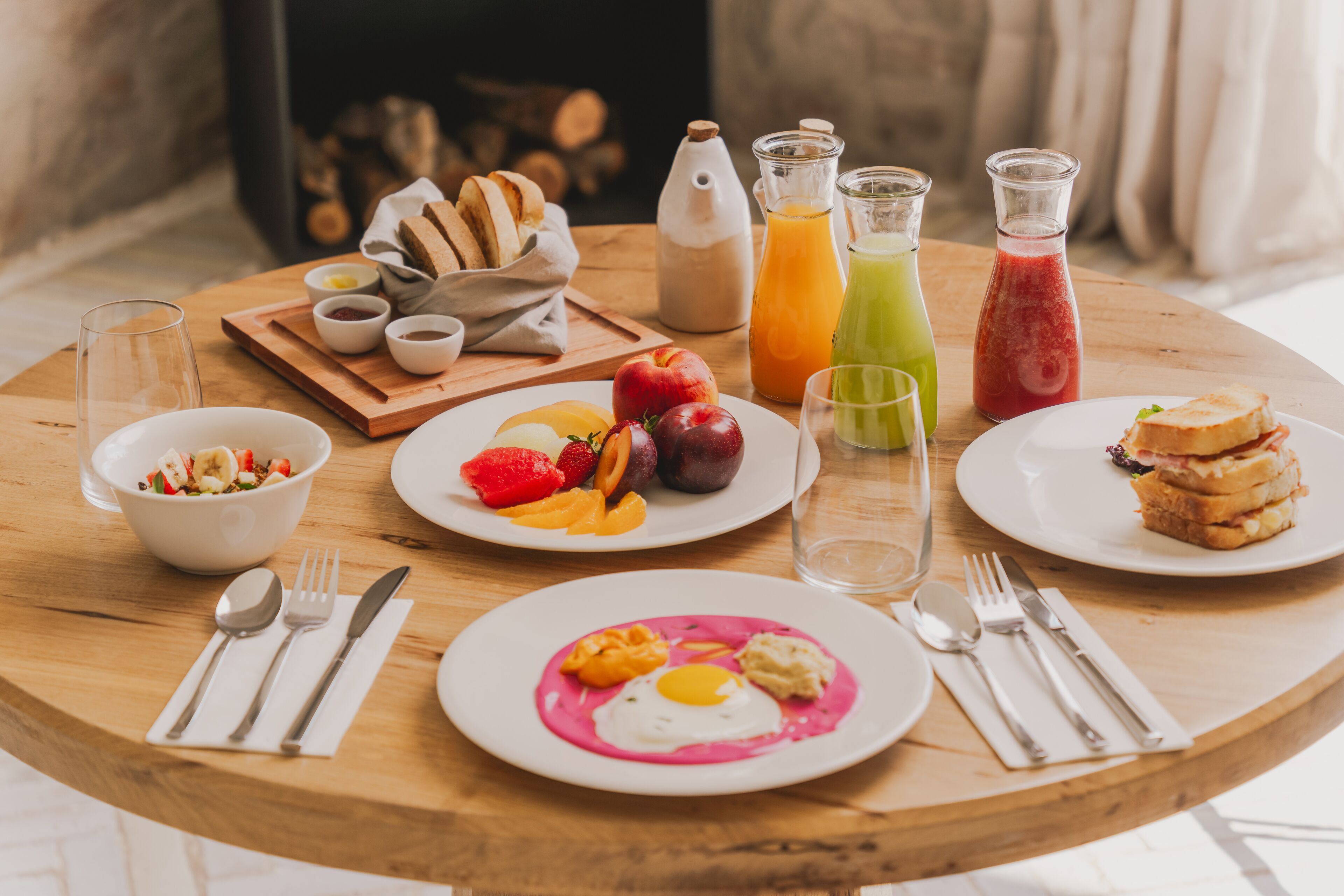 A breakfast table with various food items, drinks, and utensils.