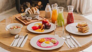 A breakfast table with various food items, drinks, and utensils.