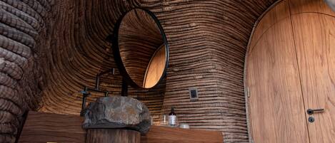A wooden interior with a circular mirror and a stone base.