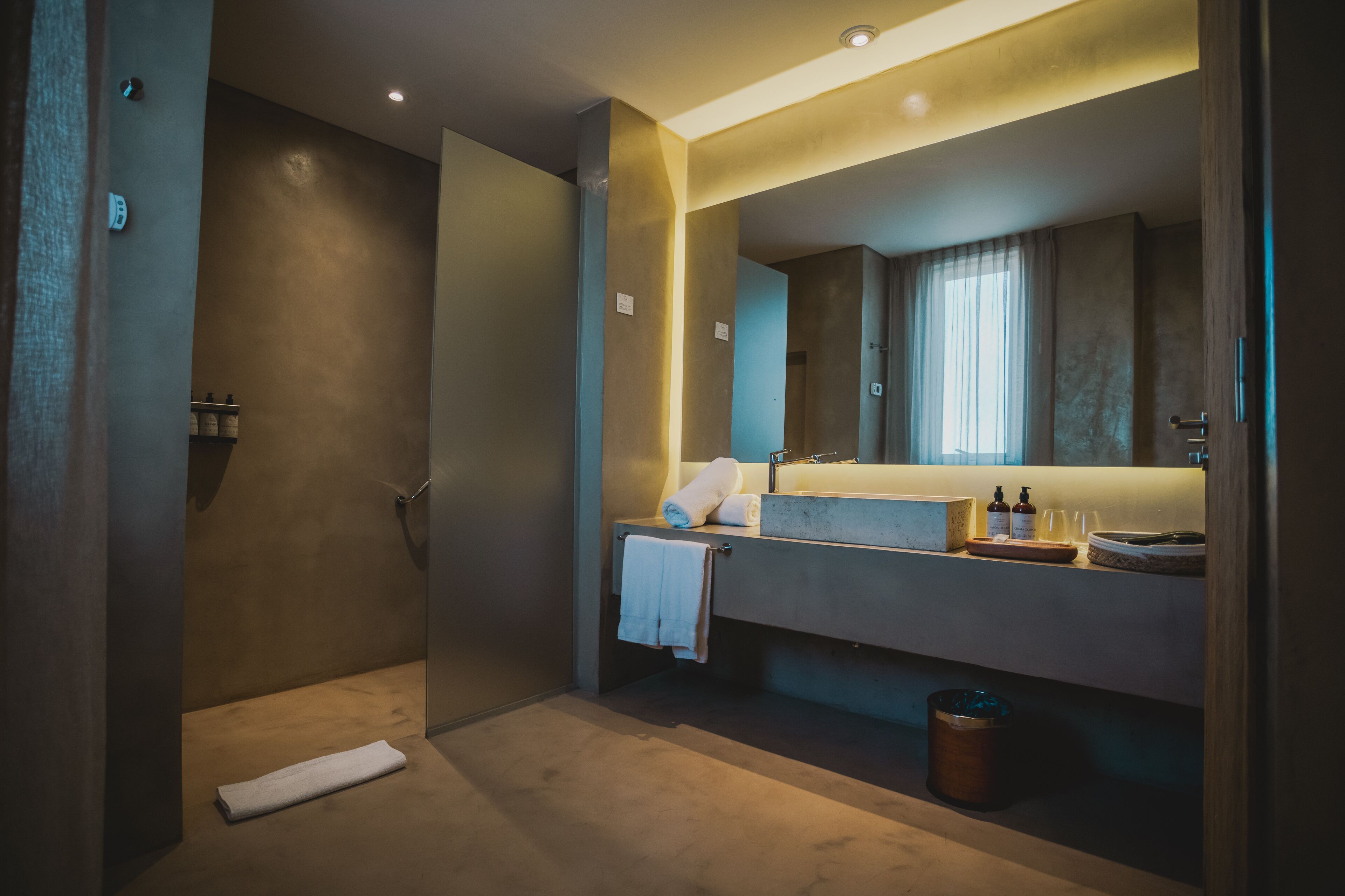A modern bathroom with a walk-in shower, a large mirror, and a vanity with a sink and towel rack.