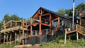 Eine mehrstöckige Holzhütte mit Balkon, Treppe und überdachter Veranda.