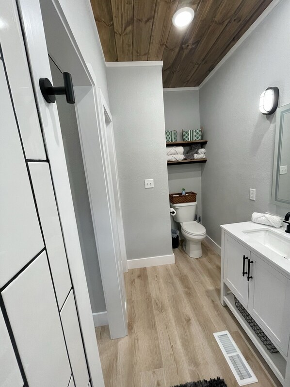 A modern bathroom with a toilet, sink, and shelves with towels. - AMAZING LAKE VIEWS DOUBLE DECK WITH HOT TUB AND 2 PORCH SWINGS (Cookson)