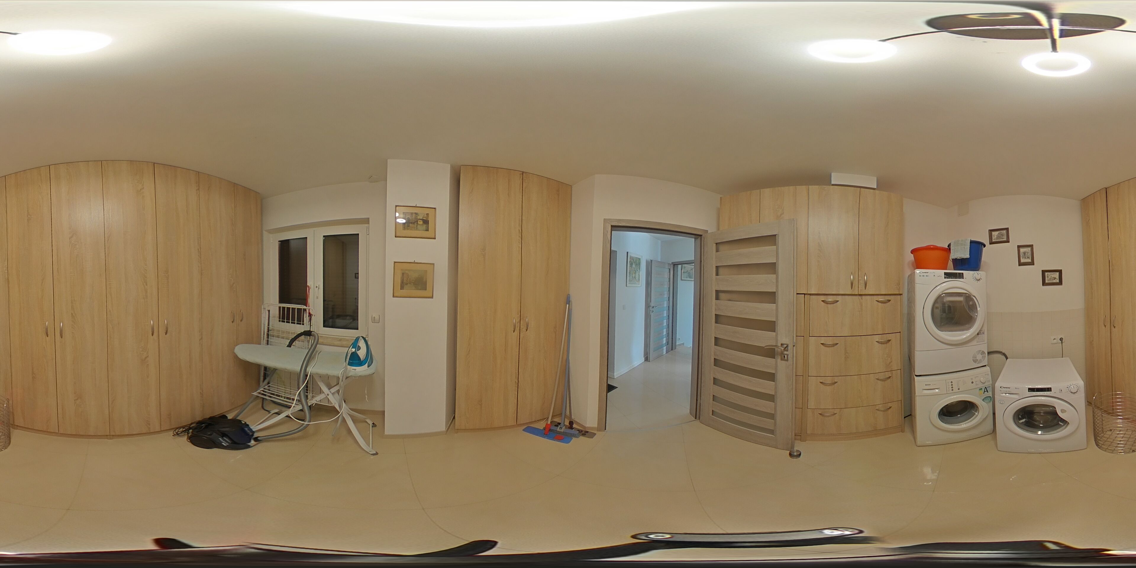 Une pièce avec des meubles de rangement en bois, un lave-linge et un étendoir.