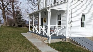A white house with a porch, a stone pathway, and a grassy yard.