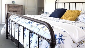 A bedroom with a bed, a dresser, and a door.