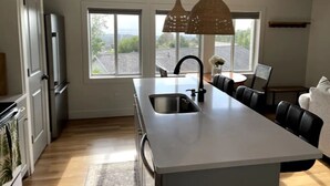 A modern kitchen with a large island, stainless steel appliances, and large windows offering a view of the outdoors. - Lovely 1-Bdrm Apt w/ Hot Tub - 5 mins from Canyons (Cottonwood Heights)