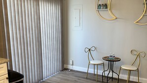 A modern living room with a wooden floor, a ceiling light fixture, and two gold-framed chairs around a small round table. - Romantic Two Bedroom Condo (Crofton)