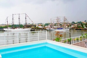 A swimming pool with a view of two tall ships docked at a harbor.