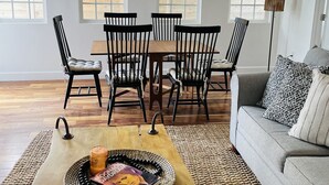 A dining area with a wooden table, chairs, and a hanging light fixture.