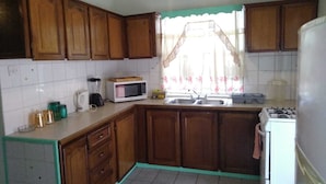 A kitchen with wooden cabinets, a microwave, a sink, and a stove. - 4 separate single bedrooms,bathrooms,living and kitchen.beach access (Rodney Bay)