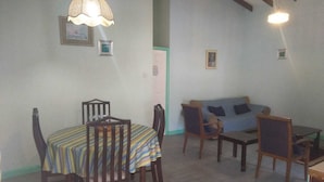 A dining area with a table and chairs, a sofa, and two hanging lamps. - 4 separate single bedrooms,bathrooms,living and kitchen.beach access (Rodney Bay)