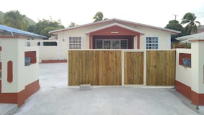A building with a red roof, a wooden gate, and a concrete driveway. - 4 separate single bedrooms,bathrooms,living and kitchen.beach access (Rodney Bay)