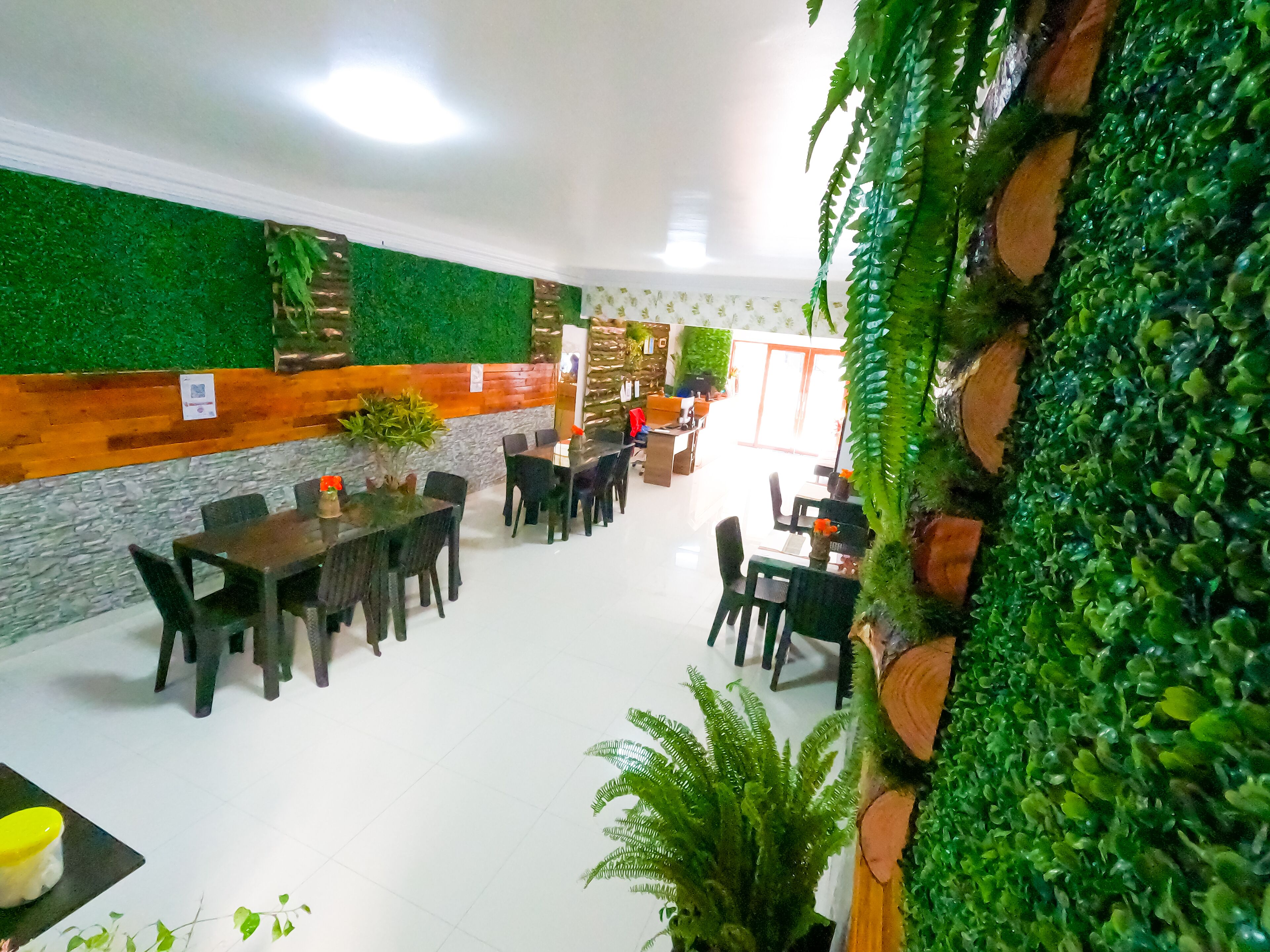 A restaurant with a green wall, wooden accents, and indoor plants.