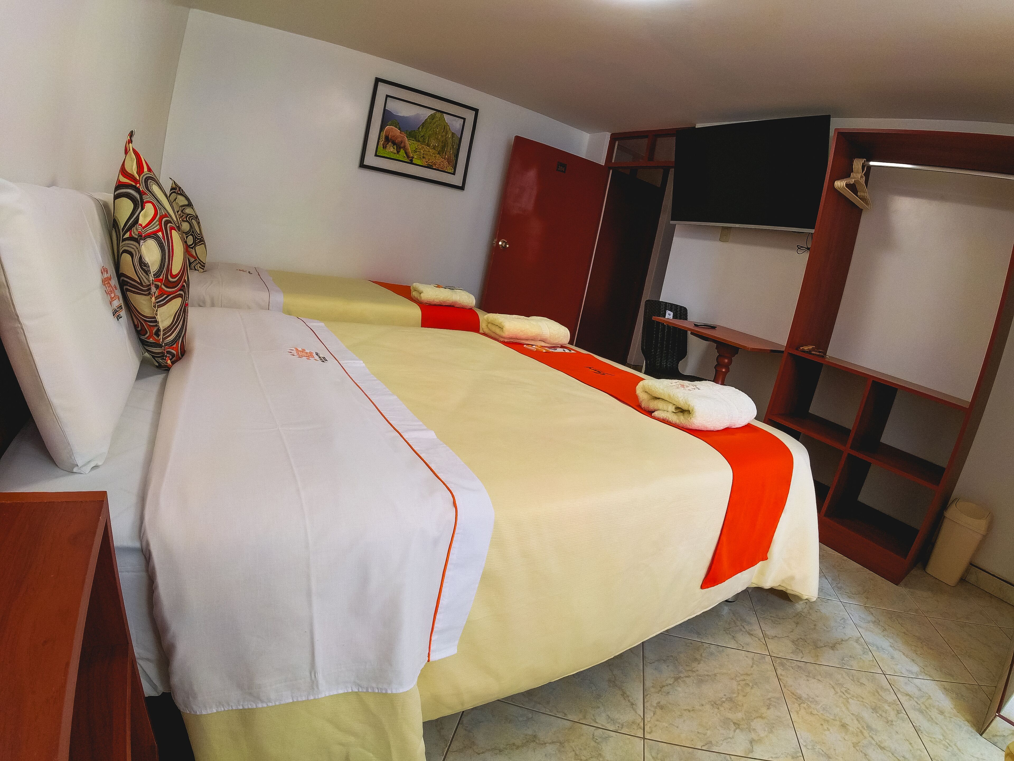 Ein Hotelzimmer mit Bett, Fernseher, Kleiderschrank und einem Bild an der Wand.