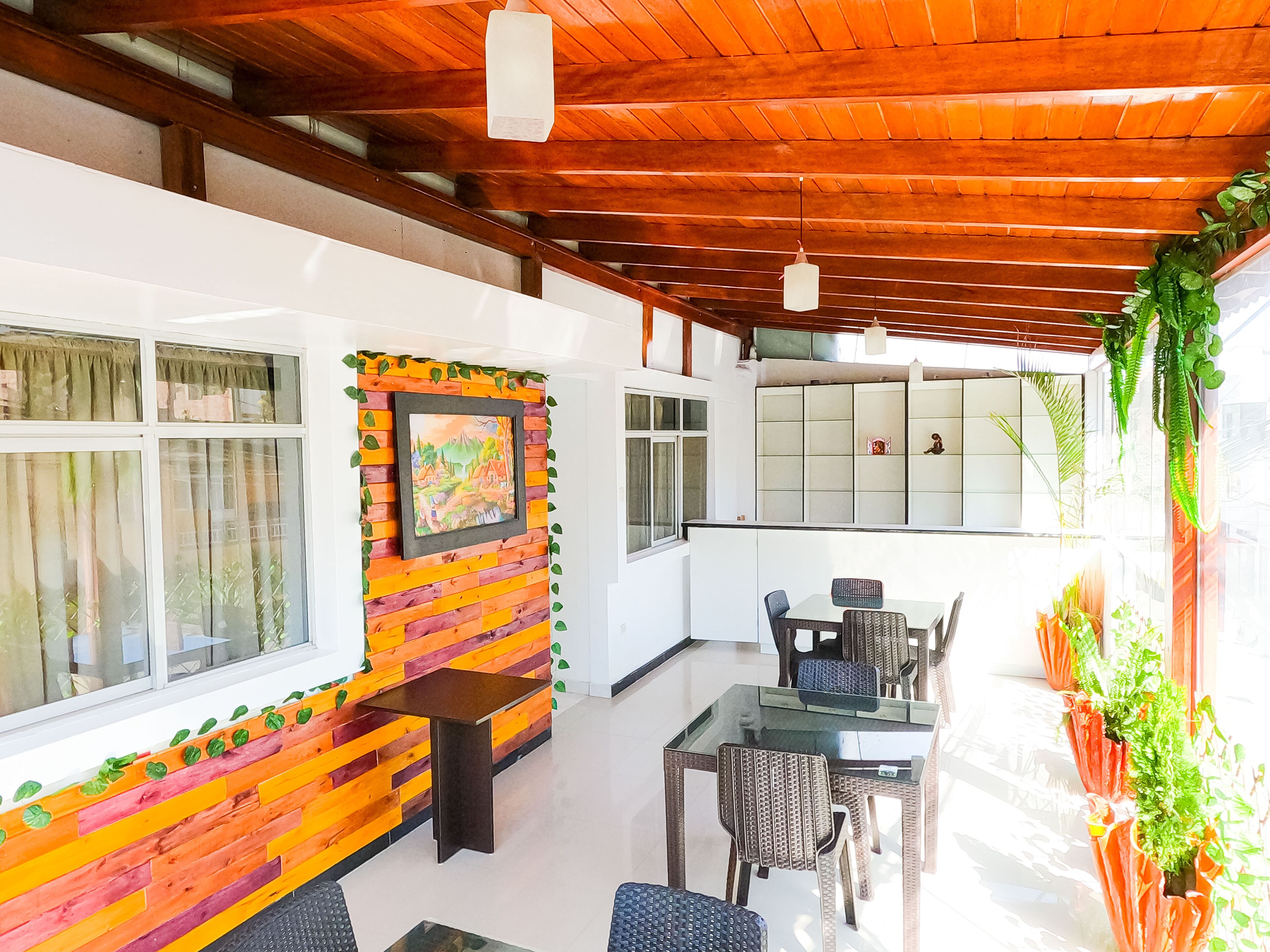 Zona pranzo con soffitto in legno, tavolo e sedie, e parete con un quadro incorniciato.