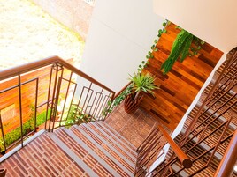 Una escalera con suelo de ladrillo, paredes de madera y barandales de metal.