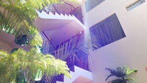 Un edificio de varios niveles con balcones, escaleras y plantas en macetas.