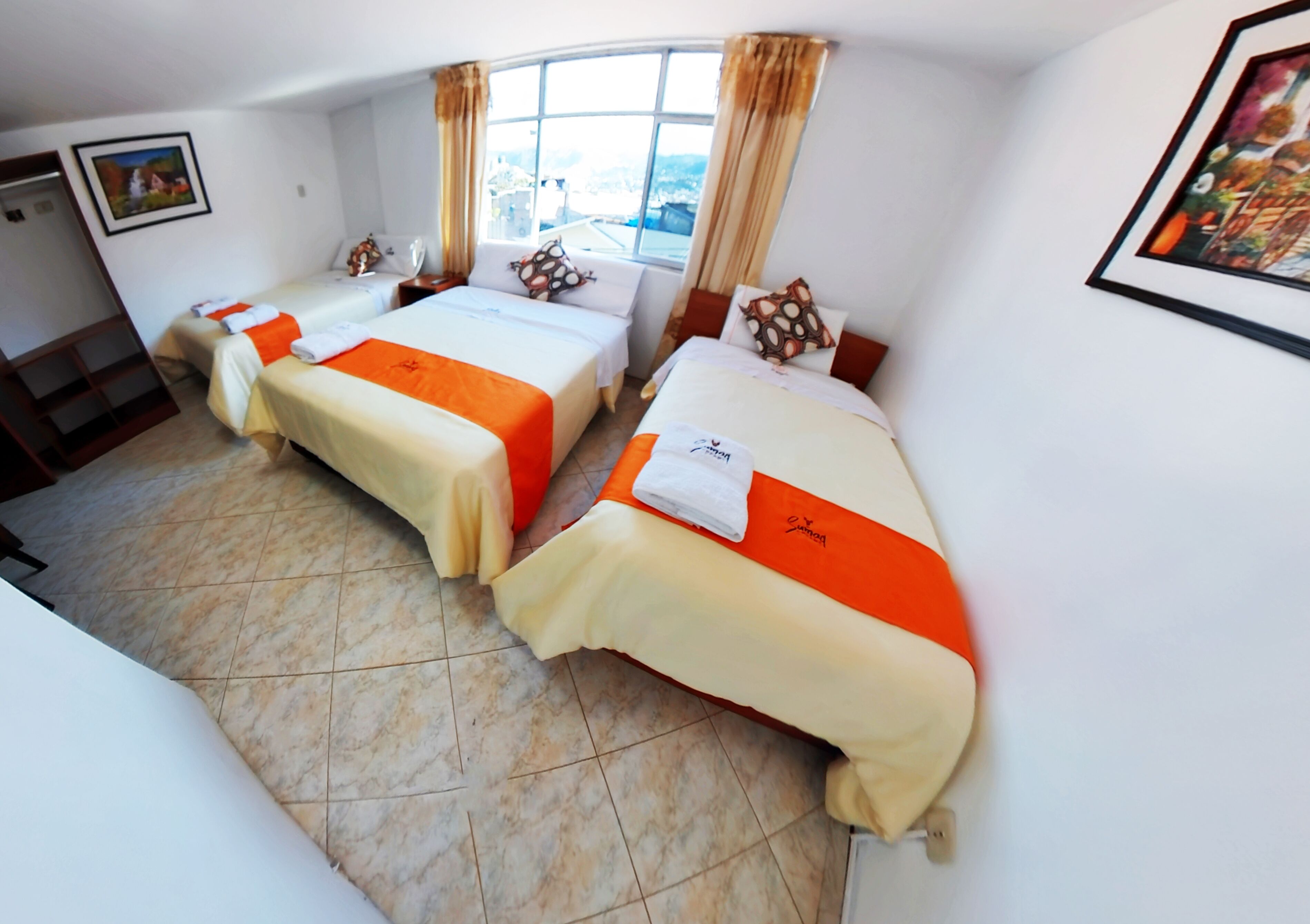 A hotel room with two beds, a large window, and a painting on the wall.
