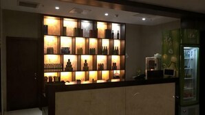 A hotel reception area with a counter, a shelf of bottles, and a refrigerator. - Qing Shui Wan Business Club (Rongcheng)