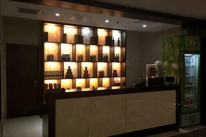 A hotel reception area with a counter, a shelf of bottles, and a refrigerator. - Qing Shui Wan Business Club (Rongcheng)