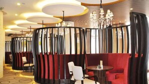 A restaurant with round tables and booths, a patterned carpet, and a modern chandelier. - Qing Shui Wan Business Club (Rongcheng)