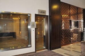 Un área de recepción con puerta de vidrio, separador de madera con televisor y un letrero que indica la ubicación.
