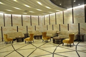 Un vestíbulo con piso de mármol, sofás y sillones dispuestos para sentarse.