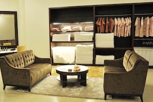 Una habitación de hotel con un conjunto de sofás, una mesa de centro redonda y un armario grande con ropa doblada.