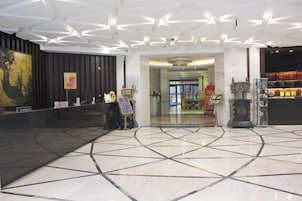 Un vestíbulo de hotel con una recepción, un cuadro abstracto de gran tamaño y un suelo de baldosas.