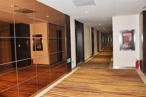 A hotel corridor with mirrored walls, a patterned carpet, and a fire extinguisher on the right. - Qing Shui Wan Business Club (Rongcheng)