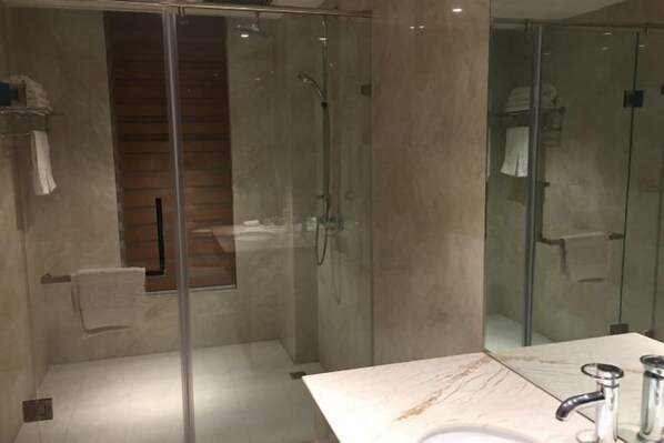 A modern bathroom with a glass-enclosed shower, a marble countertop, and a sink. - Qing Shui Wan Business Club (Rongcheng)
