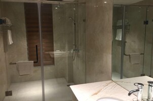 Un baño moderno con ducha de vidrio, encimera de mármol y lavabo.