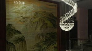 A room with a traditional Chinese landscape painting on the wall, a modern chandelier, and two crystal spheres on a table. - Qing Shui Wan Business Club (Rongcheng)