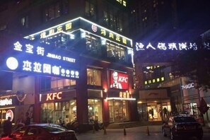 A KFC restaurant with a prominent sign, located on a busy street with other shops and a pedestrian area. - Qing Shui Wan Business Club (Rongcheng)