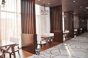 Un comedor moderno con paneles de madera, sillas blancas y una alfombra estampada.