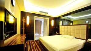 A hotel room with a bed, a desk, a mirror, and a door leading to another room. - Qing Shui Wan Business Club (Rongcheng)
